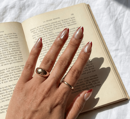 Hand with manicured nails and rings on an open book